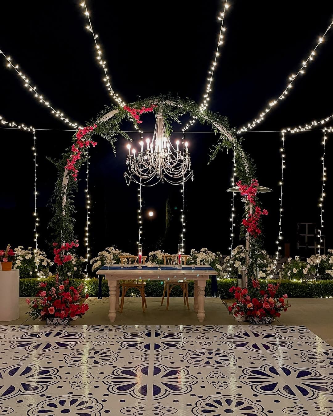 Blue and white tile-pattern dance floor rental lit by string lights at an evening reception