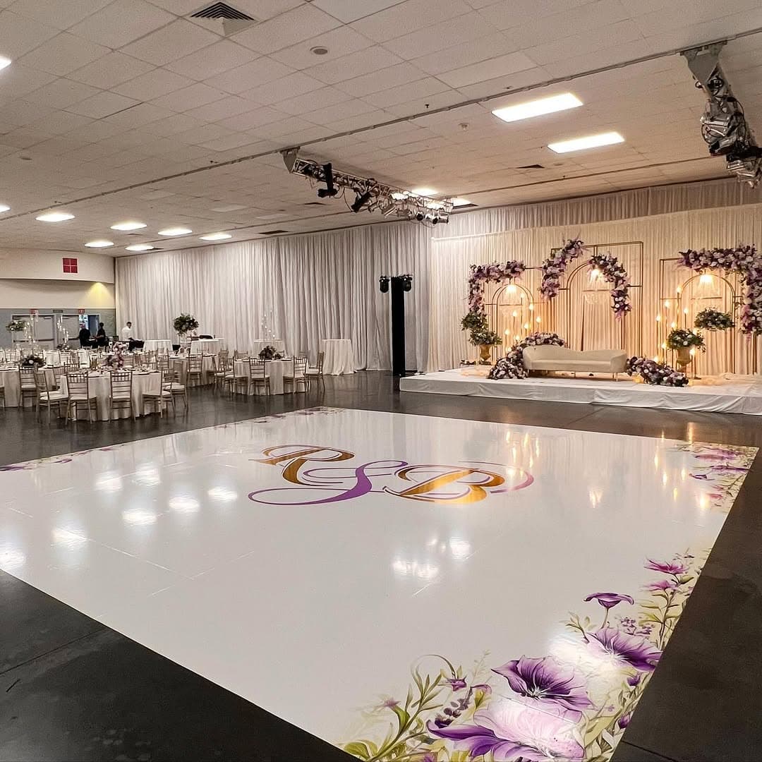 Full view of a white monogram dance floor rental set into a black ballroom floor
