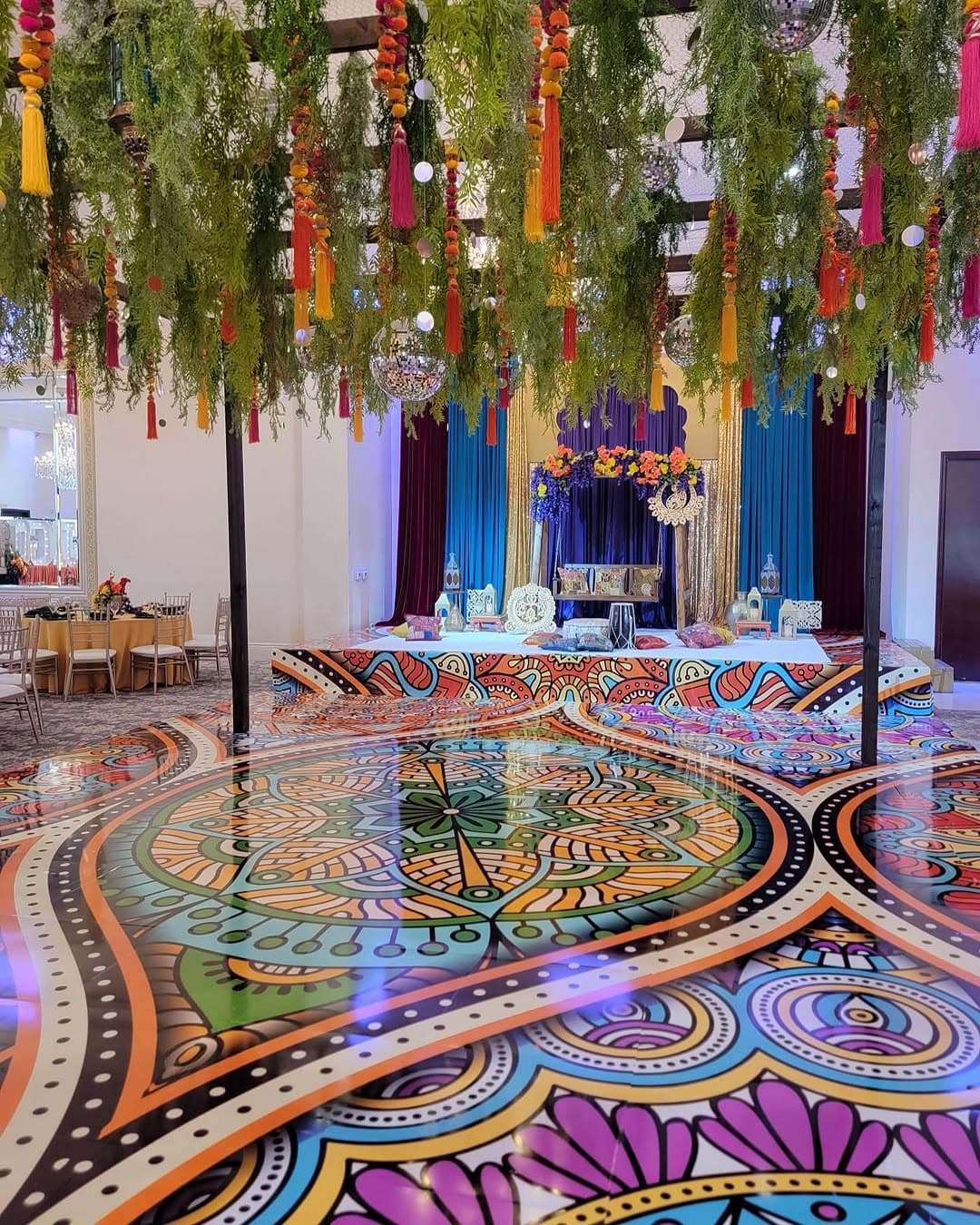 Bright mandala dance floor rental in a hall dressed with hanging greenery