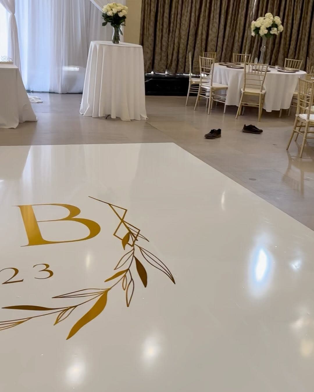 Ivory dance floor rental with a single gold initial and laurel design